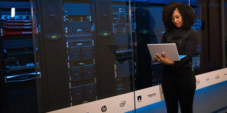IT-Fachkraft arbeitet mit Laptop an Server-Racks als Symbol für laufenden IT-Support und Managed IT