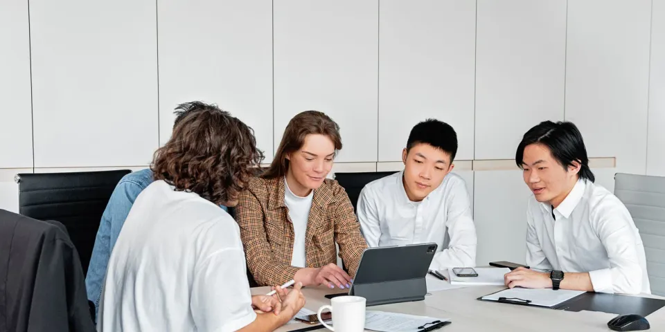 Vier Personen besprechen ein Projekt an einem Tisch mit Tablet und Unterlagen