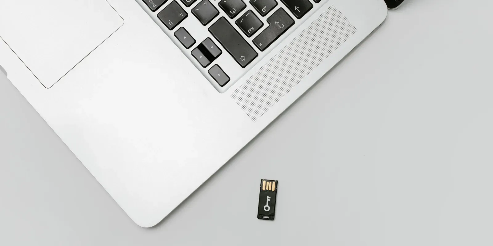 Laptop mit einem USB-Sicherheitsschlüssel daneben als Symbol für die Absicherung besonders wichtiger Konten mit MFA