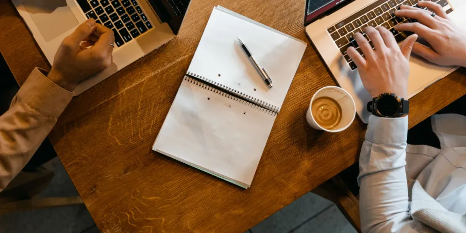 Zwei Personen arbeiten an getrennten Laptops als Symbol für den Vergleich zweier Arbeitsmodelle