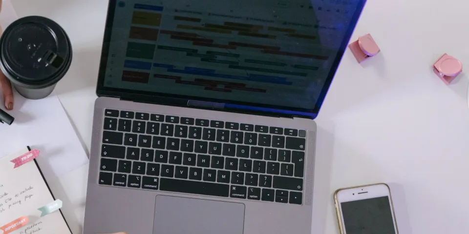 Laptop mit Zeitplanansicht neben Notizbuch und Smartphone als Symbol für die Planung einer Microsoft-365-Migration
