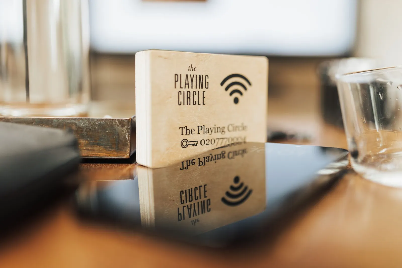 Holzaufsteller mit WLAN-Symbol neben einem Tablet und einem Glas auf einem Tisch